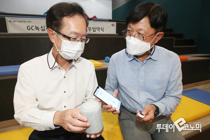 KT는 GC녹십자헬스케어와 디지털헬스케어 서비스 공동 개발 및 사업화를 위한 업무협약을 체결했다. 업무 협약식이 끝나고 양사 관계자들이 KT 기가지니 미니와 GC녹십자헬스케어 체온계가 연동되는 스마트폰 애플리케이션을 시연해보고 있다. (KT AI/DX융합사업부문장 전홍범 부사장(왼쪽), GC녹십자헬스케어 전도규 대표) 