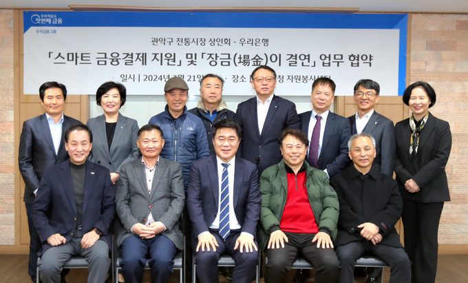 지난 21일 서울 관악구청 자원봉사센터에서 열린 우리은행과 관악구 전통시장 상인회의 '스마트 금융결제 지원 및 장금이 결연 업무협약식'에서 정진완(뒷줄 오른쪽에서 네번째) 우리은행 중소기업그룹 부행장과 정현옥(뒷줄 왼쪽에서 두번째) 우리은행 금융소비자보호그룹 부행장, 박준희(앞줄 왼쪽에서 세번째) 관악구청장, 임영업 관악구 전통시장 상인회장(앞줄 왼쪽에서 두번째)이 기념촬영을 하고 있다. (사진=우리은행)